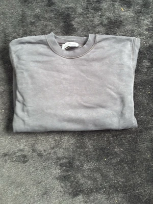 Grå sweatshirt från Stone Island - Snygg grå sweatshirt från Stone Island med klassisk rund hals och ikonisk patch på ärmen. Tröjan har ribbade muddar vid ärmslut och nederkant. Perfekt för en avslappnad och trendig stil.