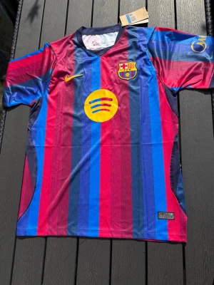 Barcelona matchtröja Lamine Yamal #10 - Säljer en officiell FC Barcelona matchtröja med Lamine Yamal och nummer 10 på ryggen. Tröjan har klassiska blå och röda ränder, gula detaljer och klubbmärke på bröstet. Tillverkad i lätt och ventilerande polyester, perfekt för fotboll eller träning.