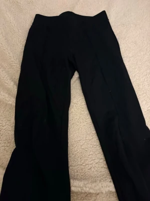 Svarta utsvängda leggings - Säljer ett par svarta leggings med utsvängda ben de ser ut som kostymbyxor fast i ett mjukare material  . Det  är gjorda i ett stretchigt material som sitter skönt på kroppen. Perfekta till sneakers eller boots för en trendig look. 