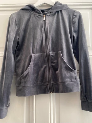 Grå velour-hoodie med luva - Mjuk och skön hoodie i grå velour med dragkedja framtill och två stora fickor + luva. Storlek XS.