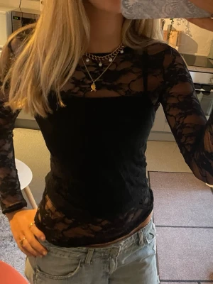 Svart långärmad spetsblus - Säljer en svart, långärmad topp i transparent spets med figurnära passform. Toppen har ett snyggt blommigt spetsmönster och är perfekt att styla med jeans eller kjol. 💕 Köpte ganska längesedan och står inget märke. Men passar xs-m