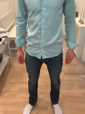 Grönvit rutig skjorta från Eton - Snygg grön och vit rutig skjorta från Eton med klassisk krage och knappar framtill. Skjortan har lång ärm och är tillverkad i bomull, vilket gör den både bekväm och stilren. Perfekt för dig som gillar en fräsch och tidlös look. Personen på bild är 186cm lång 