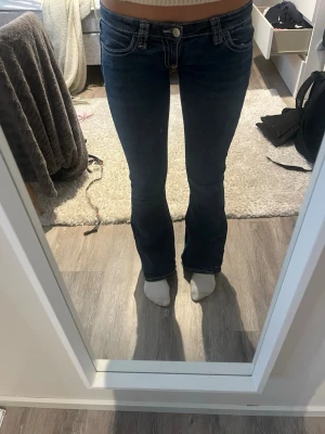 Mörkblå lowwaist bootcut jeans  - Säljer ett par mörkblå bootcut jeans med deaign på fickorna. Jeansen har låg midja. Från Gina tricot