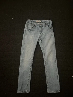 Ljusblå raka jeans - Säljer ett par ljusblå jeans med rak passform och klassisk femficksdesign. Jeansen har normal midja och stängs med knapp och dragkedja. Perfekta till en avslappnad stil och passar till det mesta i garderoben.