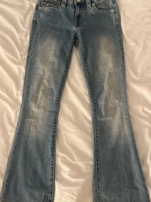 Bootcut jeans i ljusblå denim - Säljer ett par ljusblå bootcut jeans från True Religion. En liten fläck på låret men inget som syns mycket!💕