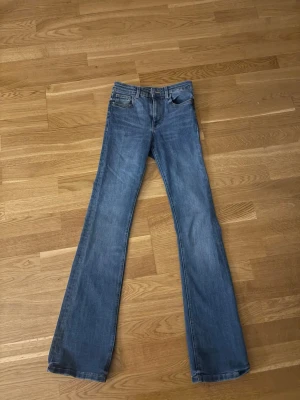 Blå bootcut jeans med hög midja - Säljer ett par klassiska blå bootcut jeans med hög midja och fem fickor. 