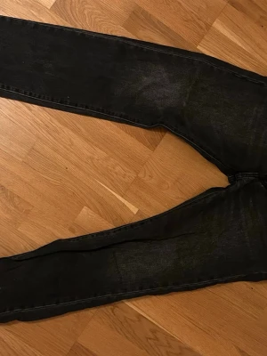 Svarta Levi's 551 Z raka jeans - Säljer ett par svarta Levi's 551 Z jeans med rak passform och klassisk femficksdesign. Jeansen har en snygg tvättad look och är tillverkade i slitstarkt denim. Perfekta för dig som gillar en tidlös och avslappnad stil. Har en liten röd fläck på benets framsida, syns dock inte från avstånd. Pris kan diskuteras