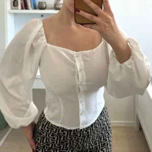 Vit blus med puffärmar och knappar - Säljer en vit blus med puffiga långärmar och knappar framtill. Sitter snyggt och markerar midjan. Nyskick