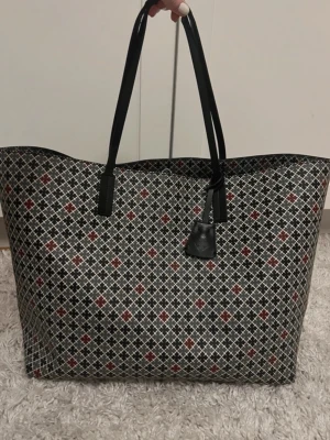 Stor By Malene Birger väska  - Stor shoppingväska med svartvita och röda geometriska mönster. Väskan har två långa svarta handtag och en svart taggdetalj framtill. Tillverkad i ett tåligt material som känns lätt att bära och rymmer mycket. Perfekt för dig som gillar stilrena men ändå unika accessoarer. Allt är som nyskick bara handtaget lite slitet därför billigare pris säljer för.❤️