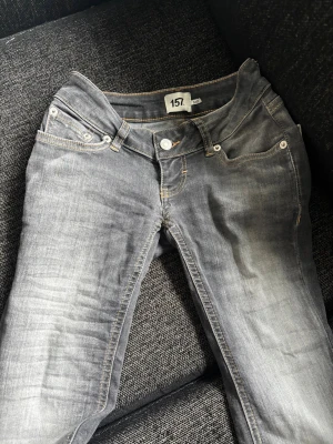 Gråa jeans  - Säljer ett par grå jeans med snyggt sliten tvätt och raka ben. Jeansen har fem fickor, silverfärgade nitar och kontrastsömmar. Passar perfekt till en avslappnad stil och är tillverkade i klassisk denim med lite stretch.