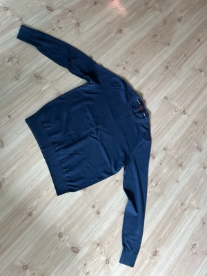 Mörkblå tröja från Morris - Snygg mörkblå tröja från Morris i 100% bomull. Klassisk rund halsringning och diskret broderad logga på bröstet. Perfekt att matcha med jeans eller chinos för en clean look.