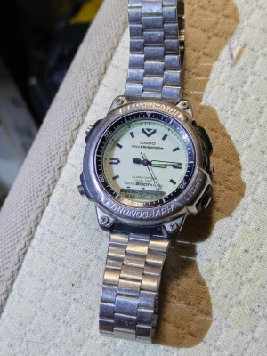 Casio Illuminator Chronograph modell AD-300, kaliber 1320 - Casio Illuminator kronografklocka med robust boett och länkarmband i silverfärgad metall. Analog och digital display, vattentät till 200 meter och tydliga knappar på sidan. Perfekt för dig som gillar sportig och funktionell stil.