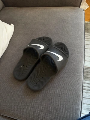 Nike tofflor  - Säljer ett par svarta Nike tofflor. Tofflorna är i väldigt bra skick och extremt bekväma. Priset kan diskuteras.