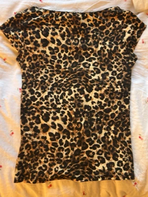 Leopardmönstrad v-ringad topp - Snygg topp med leopardmönster och v-ringning. Kortärmad modell i mjukt material som sitter skönt på kroppen. Perfekt för dig som vill sticka ut med ett djurmönster i garderoben.