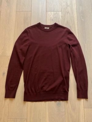 Vinröd stickad tröja - En stilren vinröd stickad tröja med rund halsringning och långa ärmar. Tröjan har ribbade muddar vid ärmslut och nederkant. Perfekt för lager på lager och enkel att matcha med olika outfits. Det är inga defekter eller något som är trasigt, men om man har npgra frågor är det alltid att bara höra av sig!👍(tröjan är 80 procent merino)