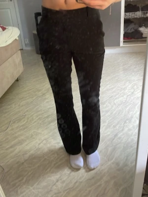 Svarta raka kostymbyxor - Säljer ett par svarta kostymbyxor med rak passform och hög midja. Byxorna har sidfickor och stängs med knapp och dragkedja. Klassisk och stilren look som passar till många olika outfits.