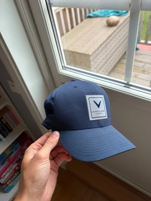Callaway Golf keps Flexfit 110 – mörkblå - Snygg golfkeps från Callaway i mörkblå färg med vit broderad/patchad logotyp framtill. Modell Flexfit 110 med justerbart snapback-spänne baktill för flexibel passform.  Sportig och stilren modell som passar perfekt både på golfbanan och till vardags. Fint begagnat skick.