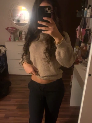 Beige stickad tröja med rund hals - Mysig beige stickad tröja med rund hals och långa ärmar. Tröjan har en avslappnad passform och ribbade muddar vid ärmslut och nederkant. Perfekt att matcha med både jeans och kjol för en enkel och snygg look.