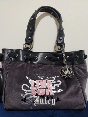 Juicy Couture daydreamer live for juicy - Juicy Couture handväska i grå sammet med svarta detaljer i konstläder. Väskan har nitar på handtagen, ett stort tryck med texten 'Live For Juicy' och en dekorativ metallberlock i form av en krona. Snygg och rymlig modell med coola detaljer.
