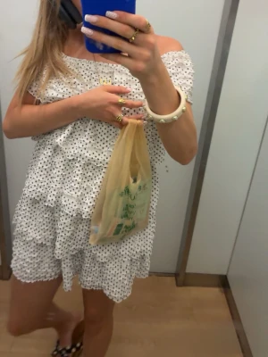 Populär Zara klänning  - Söt vit kortklänning med svarta prickar och volangdetaljer. Offshoulder-modell med luftig passform och flera lager tyg som ger en romantisk känsla. Perfekt för varma dagar och sommarens alla tillfällen.