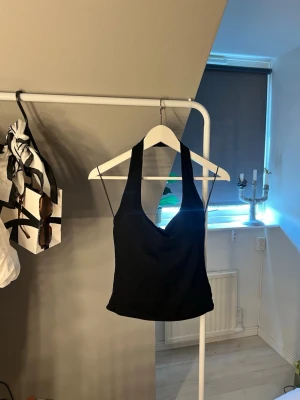 Svart topp - Snygg svart  linnetopp med djup urringning och tunna axelband. Toppen har en enkel och stilren design som passar perfekt till jeans eller kjol. Materialet känns mjukt och följsamt mot huden.