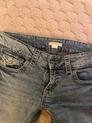 Blå bootcut jeans med låg midja - Säljer ett par blå bootcut jeans med låg midja och klassiska fem fickor. Jeansen har snygga detaljer på bakfickorna och är i ett mjukt denimtyg. Perfekta för en avslappnad och trendig look. Strl 158 men är 163 och de passar bra.