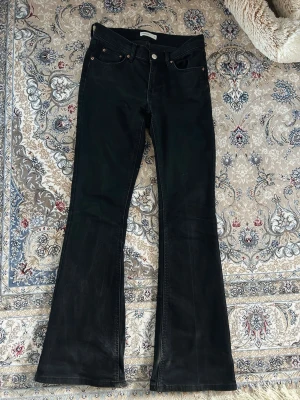 Svarta utsvängda jeans - Säljer ett par svarta jeans med utsvängda ben och klassisk femficksmodell. Jeansen har låg midja och raka sömmar, perfekta för en trendig och avslappnad look. Materialet är stretch för extra komfort.