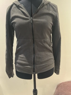 Mörkgrå hoodie med dragkedja - Snygg mörkgrå hoodie med lite sliten dragkedja framtill och två fickor. 