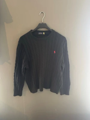 Svart kabelstickad tröja Polo Ralph Lauren - Snygg polo Ralph Lauren sweatshirt, den ser helt ny ut i skicket inget märke eller något, ser ju som att vara helt ny. Hör av er vid frågor om pris och annat!✅👍