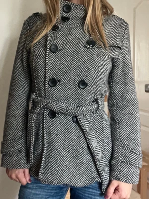 Svartvit rutig vintage kappa  - Vintage kappa med fiskbensmönster, dubbelknäppning, hög krage och bälte i midjan. Ganska tjock och varm, passar både höst och vinter💞 // strl S/M