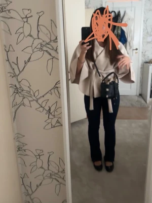 Beige kappa med knytskärp - Säljer en beige kappa med vida trekvartsärmar och knytskärp i midjan. Kappan har en avslappnad passform och är tillverkad i ett mjukt tyg som ger en stilren look. Perfekt för dig som gillar minimalistisk och trendig stil.