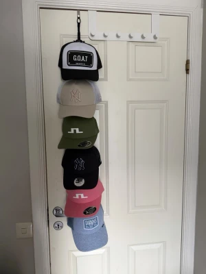 Kepsar - Säljer ett paket med sex olika kepsar i olika färger och stilar. Inkluderar svart och vit truckerkeps med G.O.A.T-tryck, beige och svart New York Yankees-kepsar, grön och rosa keps med vit logga samt ljusblå keps från Djinns. Perfekt för dig som vill variera din stil.