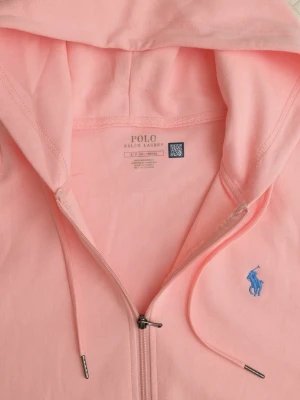 Ljusrosa hoodie från Polo Ralph Lauren - Snygg ljusrosa hoodie från Polo Ralph Lauren med dragkedja framtill, huva med snörning och kängurufickor. Ikoniska blå loggan broderad på bröstet. Tillverkad i mjuk bomull, perfekt för en chill och avslappnad stil.