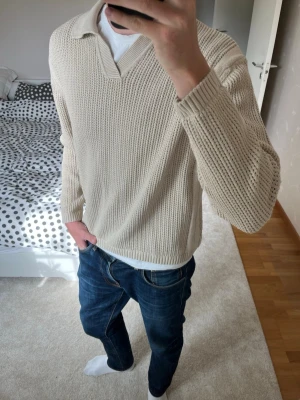 Beige stickad tröja med krage från Zara - Säljer en beige stickad tröja med krage och v-ringad öppning. Tröjan är i fint skick utan defekter! Tröjan är i L men sitter som M 