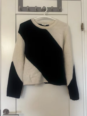 Vit och blå stickad tröja - Snygg stickad tröja i vit med breda blåa diagonala blockränder. Tröjan har rund halsringning och långa ärmar. Perfekt för dig som gillar grafiska mönster och vill ha en unik look. Stlk 158/164