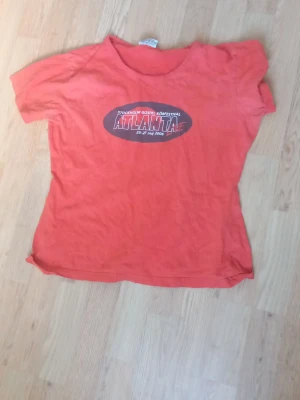 Röd t-shirt med Atlanta-tryck - Röd t-shirt med tryck 'ATLANTA' och text om Stockholm Gospel Körfestival på bröstet. Klassisk rund hals och korta ärmar. Tillverkad i mjukt bomullstyg, perfekt för en avslappnad stil.