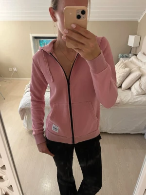 Rosa zip-hoodie med huva - Säljer en rosa hoodie med dragkedja och huva. Tröjan har fickor framtill, ribbade muddar vid ärmar och nederkant samt snören i huvan. Använd fåtal gånger men väldigt bekväm💗