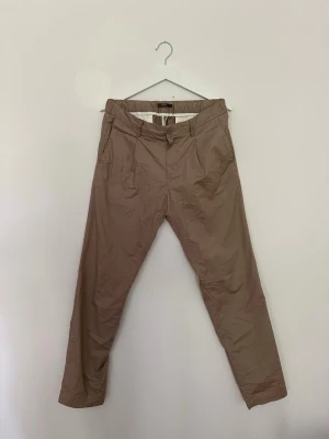 Boggie byxor  - Boggi Milano-byxor i brun färg med elastisk midja. Begagnade men i gott skick utan anmärkningar. Bekväma och stilrena byxor som passar både till vardag och mer uppklädda tillfällen. Säljs i befintligt skick, se bilder för detaljer.