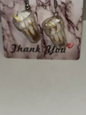 Örhängen med milkshake-design - Unika örhängen formade som milkshakes med vispgrädde och sugrör. Färgerna är vitt,brunt och de är tillverkade i plast med detaljer som liknar glas och grädde. Perfekta för dig som gillar lekfulla accessoarer.