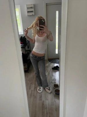 Grå low waist bootcut jeans - Säljer ett par grå low waist jeans med bootcut passform. Jeansen har klassisk femficksdesign och bälteshällor. Snygg tvättad look som ger en avslappnad vibe. Perfekta för dig som gillar Y2K-stil och vill ha ett par trendiga jeans i garderoben.