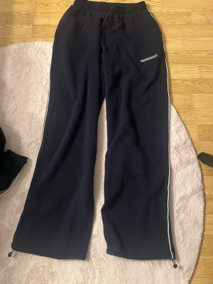 Iets frans mjukis - Säljer ett par mörkblå mjukisbyxor från Urban Outfitters - Iets Frans med vita detaljer längs sidorna och elastisk midja. Byxorna har raka ben och justerbar dragsko vid benslut. Perfekta för chill dagar eller på dansgolv. Storlek xxs men väldigt stor i storlek (därav säljer) mer som M. Beställde och fick hem idag, kunde inte returnera så därför säljer jag för samma pris som om det vore retur. Inga defekter naturligtvis, ser ut så på bild men inge vidare kvalitet på min kamera. 