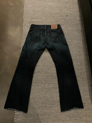 Levi's 512 Bootcut jeans mörkblå - Säljer ett par Levi's 512 Bootcut jeans i mörkblå denim. Klassisk femficksmodell med bootcut passform och snygga kontrastsömmar. Perfekta för dig som gillar en retro och avslappnad stil. Jeans med ikoniska Levi's-detaljer och etikett bak.