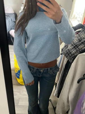 Ljusblå stickad tröja från Vero Moda - Supermysig ljusblå stickad tröja från Vero Moda. Tröjan har en klassisk rund halsringning, ribbade muddar och är långärmad. Perfekt för lager-på-lager och chill dagar. Enkel och stilren design som passar till det mesta. Tröjan har en liten fläck som du kan se på sista bilden, den syns bara i vissa ljus.
