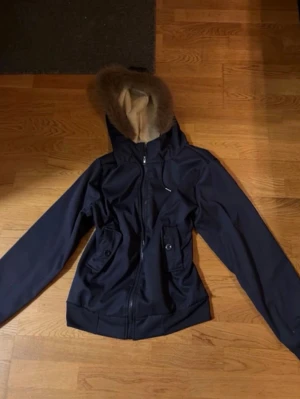 Y2K hoodie med fluff - Snygg mörkblå hoodie med dragkedja och två stora fickor framtill. Hela tröjan/jackan är fodrad med mjukt beige tyg och har en kant av fluff som ger extra stil. Perfekt för kyliga dagar och riktigt skön att bära. Den är i storlek M men passar S ganska bra. Jag vet inte vart den är köpt och jag fick den i julklapp förra året!