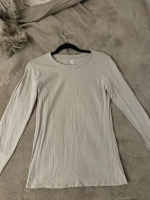 Beige grå  långärmad basic topp - En enkel och stilren ljusgrå långärmad topp med rund halsringning. Tillverkad i mjuk bomull, perfekt att matcha med jeans eller kjol. Snygg och clean look som funkar till det mesta.