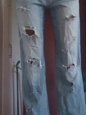 Ljusblå ripped jeans från ONLY - Säljer ett par ljusblå jeans från ONLY med flera stora slitningar och hål på benen. Jeansen har raka ben och perfekta för dig som gillar streetstyle
