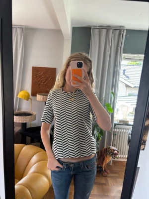 Svartvit mönstrad topp med halvärm - Säljer en svartvit topp med grafiskt randigt mönster. Toppen har rund halsringning och halvärm, samt en rak passform. Perfekt till jeans eller kjol för en cool och modern look.