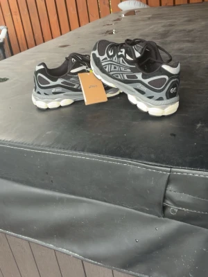 Svarta och grå ASICS GEL sneakers - Säljer ett par snygga ASICS GEL sneakers i svart och grå med vita detaljer. Skorna har en chunky sula och klassisk snörning. Perfekta för dig som gillar sportig stil och vill ha bekväma skor till vardags. Materialet är syntet och mesh för bra andningsförmåga.