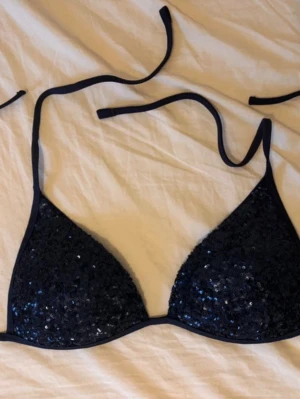 Calzedonia paljett bikini - En mörkblå bikiniöverdel från Calzedonia, som har aldrig använts eftersom den var för stor på mig. Är i storlek L/85B. Lägg gärna bud/ prisförslag som är rimligt. Ifall bild på önskas är det bara att skriva. Sista bilden är mått i cm. 