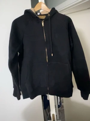 Svart hoodie med dragkedja från Burberry - Hej! Jag säljer nu en Burberry tröja som är i storlek M står XL men det är fel på tröjan. Den är helt ny, bara testat och jag tyckte inte om den som jag hade tänkte.
